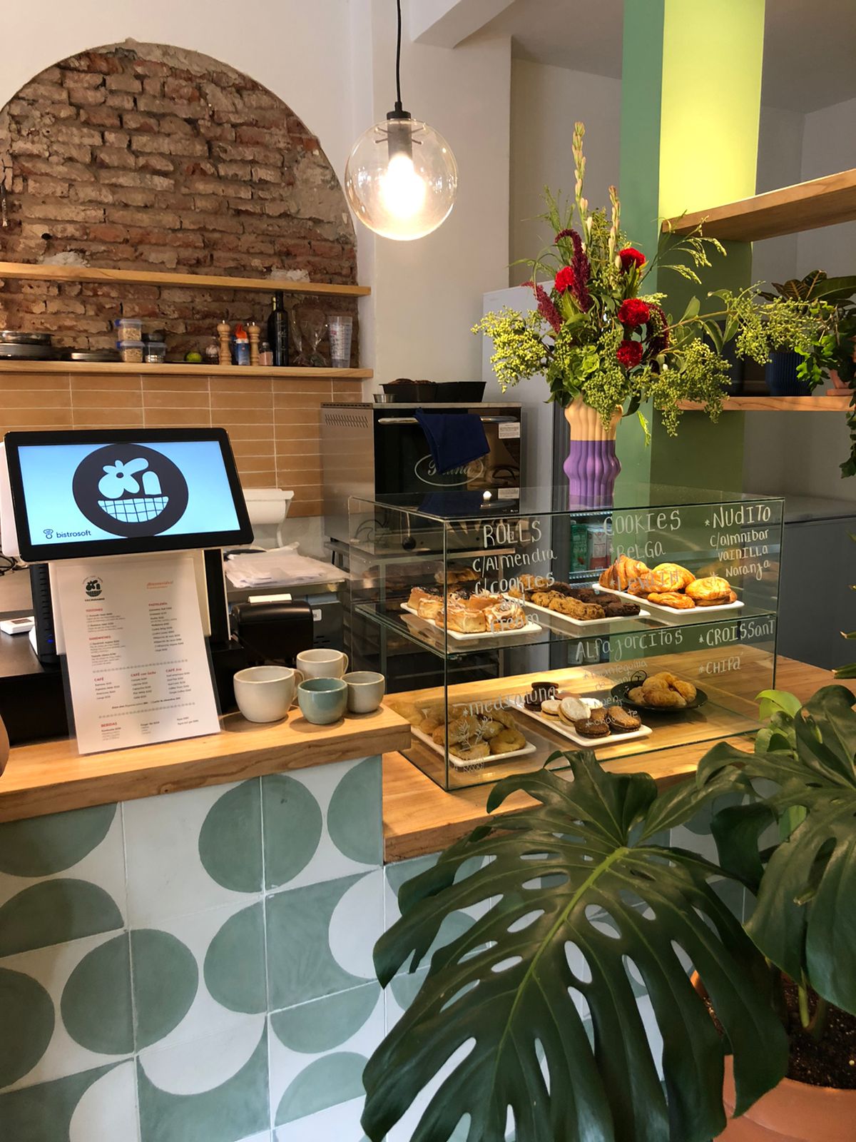 Interior de Vecindario Café y Plantas, mostrador con pastelería y plantas